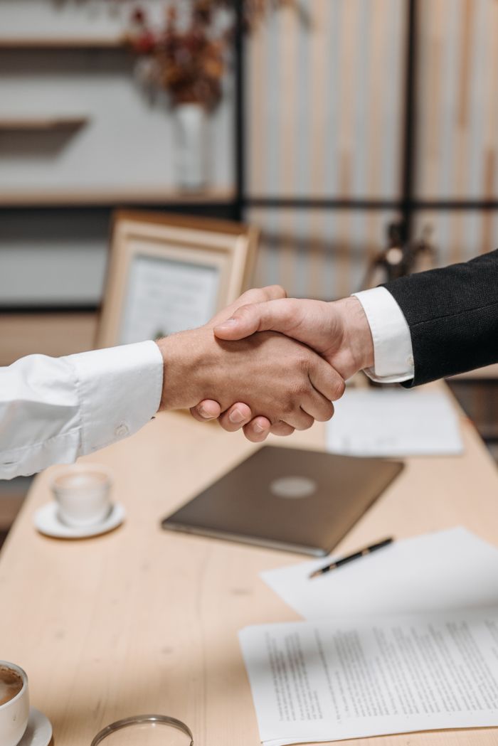 Mastering the First Impression: Your intriguing post title goes here Close-up of two people shaking hands in an office, symbolizing agreement and partnership.