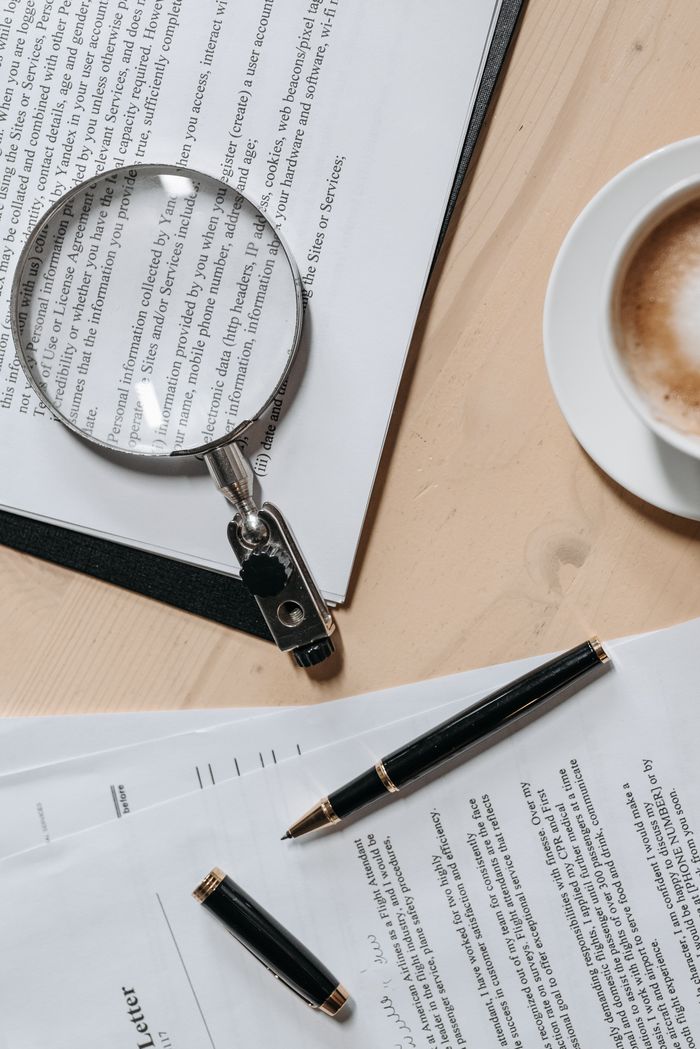 about-us Top view of documents with a magnifying glass and pen, ideal for business or legal themes.